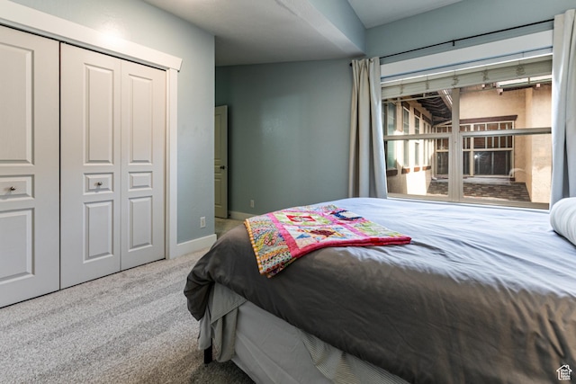 carpeted bedroom with a closet and baseboards
