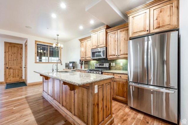 3033 Canyon Links Dr, Park City, UT 84098 - kitchen with stainless steel appliances, light wood-style floors, a center island with sink, tasteful backsplash, and light stone countertops