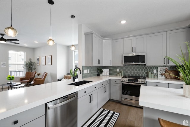 3478 S Wick Ct Unit 61, South Salt Lake, UT 84115 - kitchen featuring stainless steel appliances, a sink, light countertops, tasteful backsplash, and decorative light fixtures