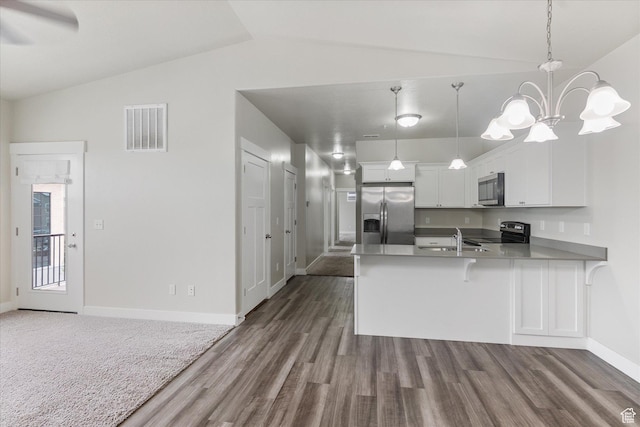 kitchen featuring appliances with stainless steel finishes, a peninsula, vaulted ceiling, dark wood finished floors, and baseboards