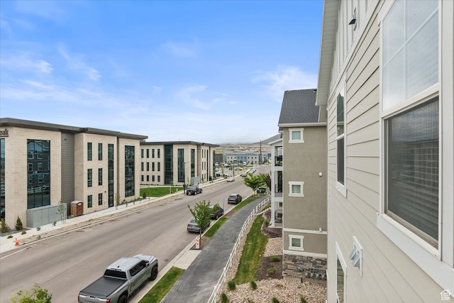 view of asphalt street featuring sidewalks, curbs, and a residential view