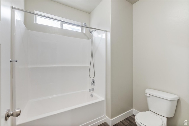bathroom featuring baseboards, toilet, wood finished floors, and shower / bath combination