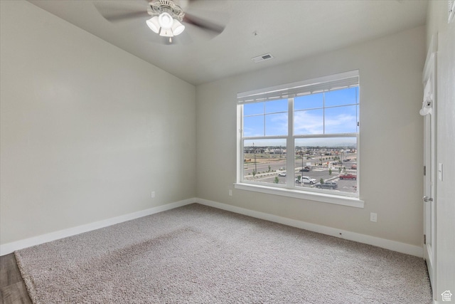 carpeted spare room featuring baseboards and a ceiling fan