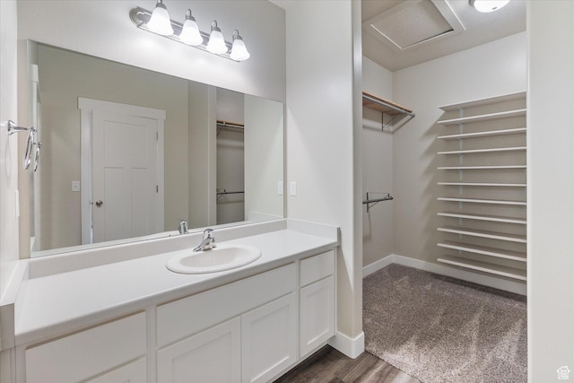 full bath featuring a walk in closet, vanity, wood finished floors, and baseboards