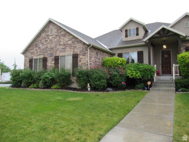 craftsman inspired home featuring a front yard, stone siding, and roof with shingles