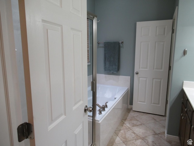 full bathroom with vanity, a garden tub, and tile patterned flooring