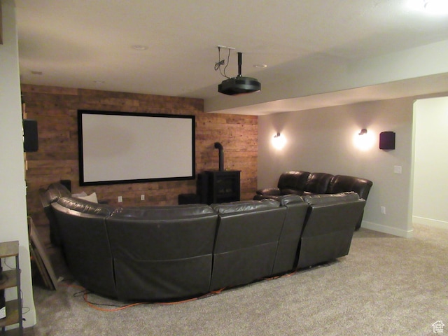 home theater featuring wooden walls, a wood stove, carpet floors, an accent wall, and baseboards