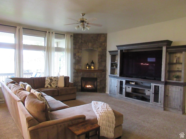 carpeted living area featuring ceiling fan and a stone fireplace