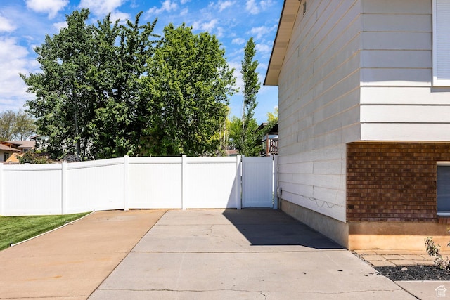 view of side of property featuring fence, brick siding, and a gate