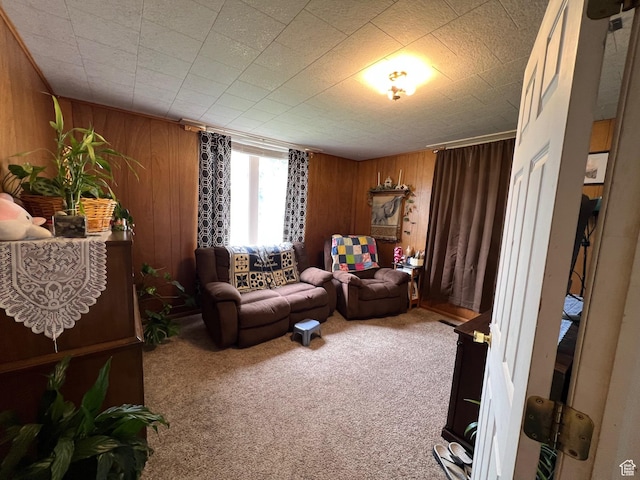 sitting room featuring wood walls and carpet flooring