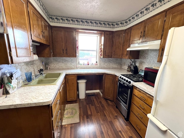 kitchen featuring under cabinet range hood, stainless steel electric stove, a sink, dark wood finished floors, and light countertops