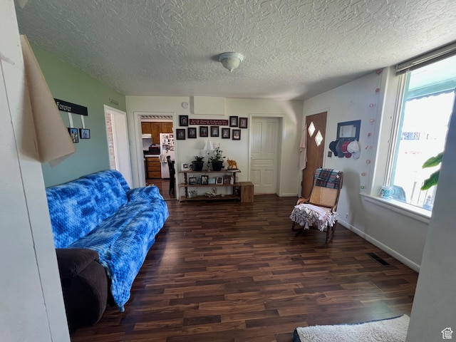 living area featuring plenty of natural light, wood finished floors, a textured ceiling, and baseboards