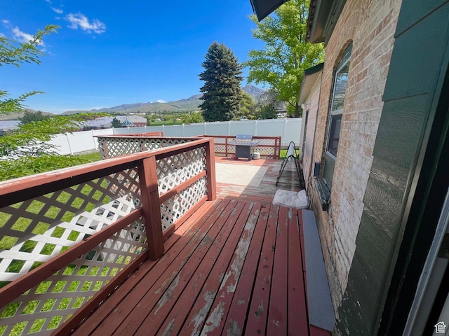 wooden deck with a mountain view, outdoor dining area, and fence