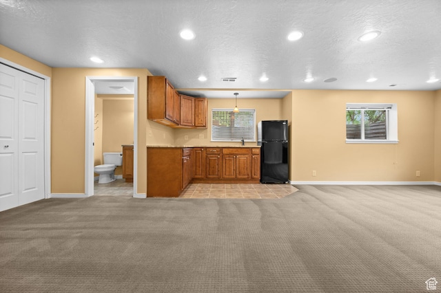 kitchen with freestanding refrigerator, light carpet, baseboards, recessed lighting, and brown cabinets