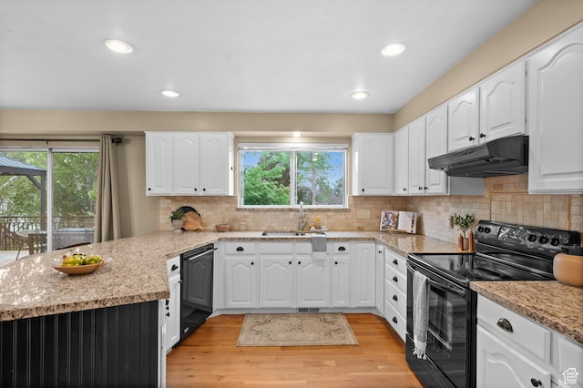 kitchen with under cabinet range hood, black appliances, a sink, a peninsula, and light wood-type flooring