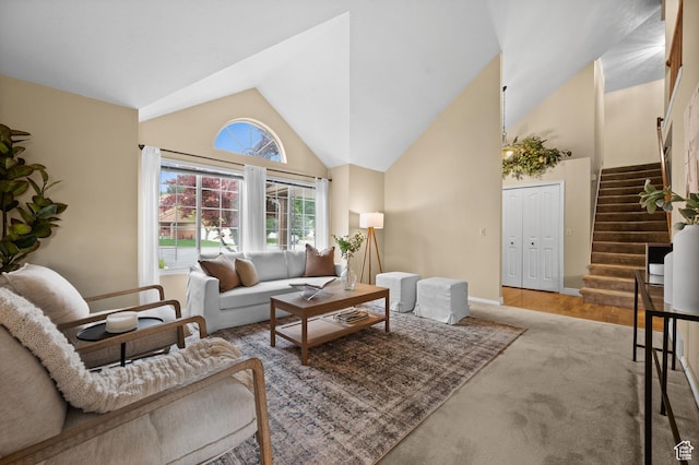 carpeted living area with stairs, high vaulted ceiling, and baseboards