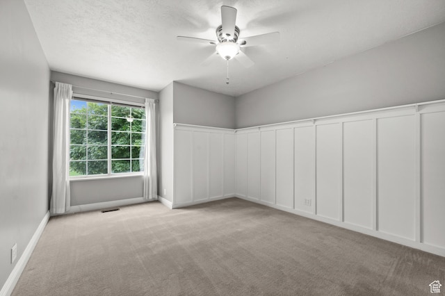 empty room featuring carpet flooring, a ceiling fan, baseboards, and a textured ceiling