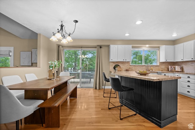kitchen featuring white cabinetry, decorative backsplash, light wood-style flooring, hanging light fixtures, and recessed lighting
