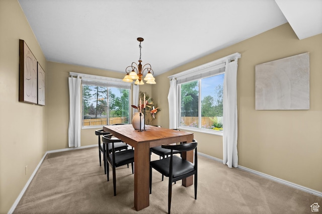dining space featuring a chandelier, light colored carpet, and baseboards