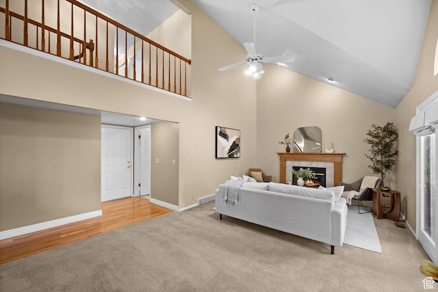 living room with light colored carpet, high vaulted ceiling, a tile fireplace, ceiling fan, and baseboards