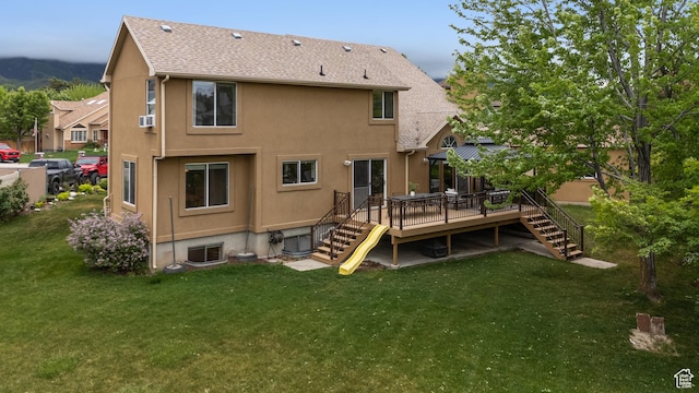 back of property featuring stairs, a wooden deck, a yard, and stucco siding