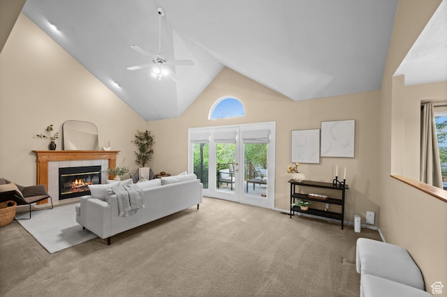 living area with ceiling fan, a tiled fireplace, high vaulted ceiling, and carpet