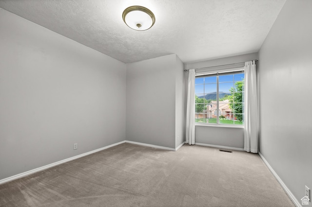 empty room featuring a textured ceiling, carpet, and baseboards