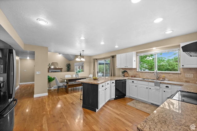 kitchen featuring black appliances, a peninsula, a sink, white cabinetry, and decorative backsplash