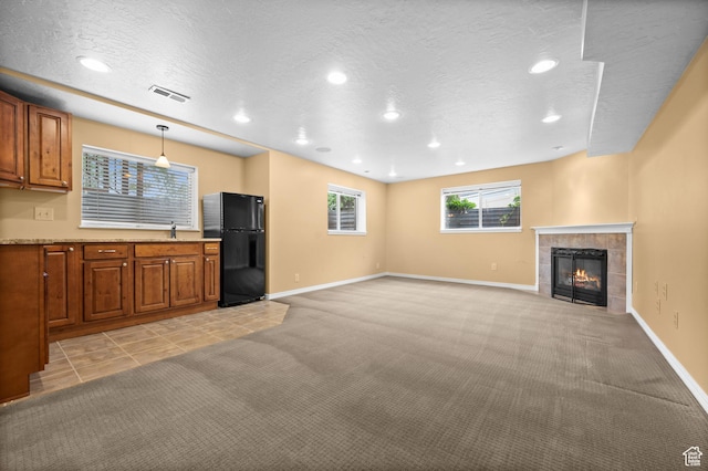 unfurnished living room featuring a fireplace, light colored carpet, recessed lighting, baseboards, and a textured ceiling