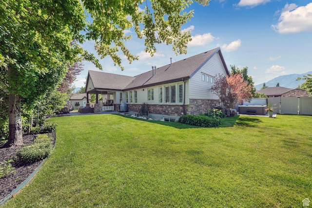 5982 N Rollins Ranch Rd W, Mountain Green, UT 84050 - back of property featuring a hot tub, stone siding, a patio, roof with shingles, and outdoor lounge area