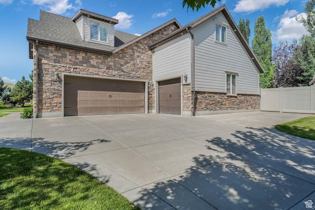 5982 N Rollins Ranch Rd W, Mountain Green, UT 84050 - view of home's exterior featuring stone siding, driveway, and a garage