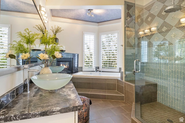 bathroom with a stall shower, a garden tub, tile patterned flooring, a fireplace, and double vanity