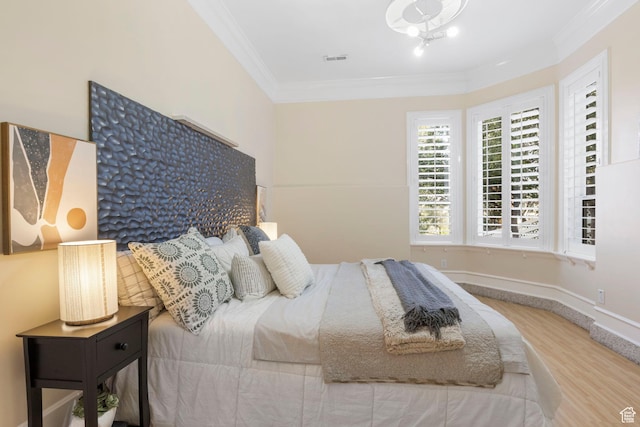 bedroom with ornamental molding, wood finished floors, and baseboards