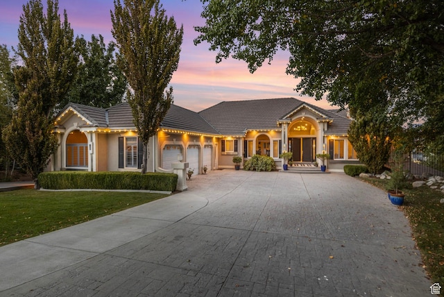 view of front of home with an attached garage, a front yard, concrete driveway, and a tiled roof