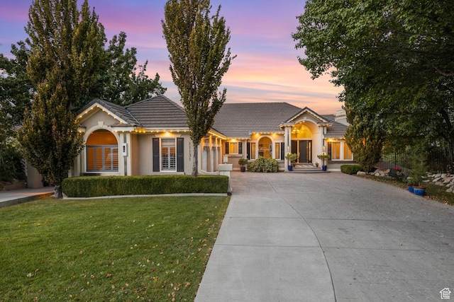 view of front of home featuring driveway, a front yard, a tiled roof, and stucco siding