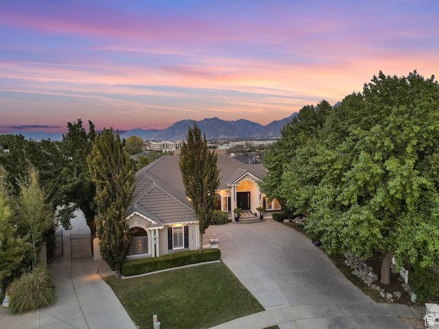 view of front facade with concrete driveway, a tiled roof, a gate, stucco siding, and a mountain view