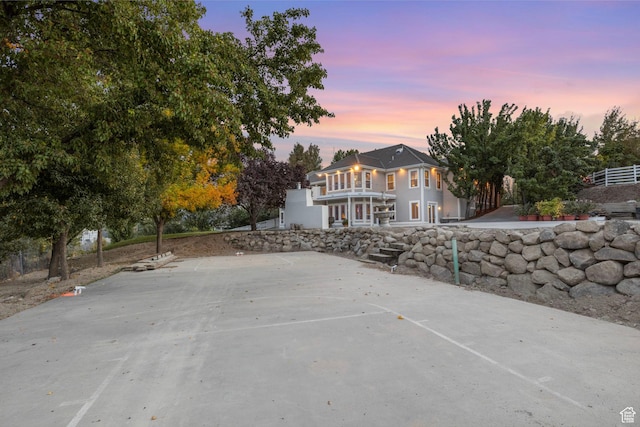 back of house at dusk featuring a balcony and basketball court