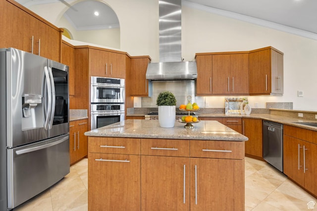 kitchen with stainless steel appliances, extractor fan, a center island, light stone counters, and brown cabinets