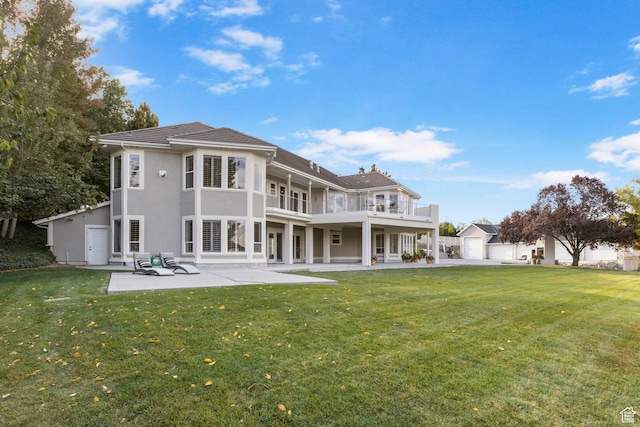 rear view of house featuring a yard, a balcony, stucco siding, and a patio area