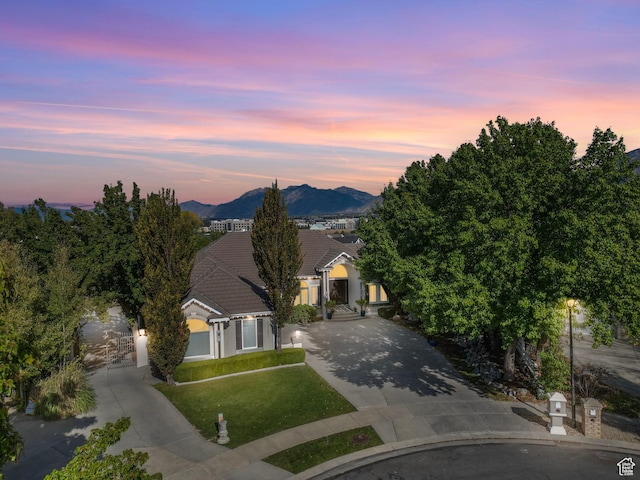 view of front of home featuring a tile roof, concrete driveway, a lawn, and a mountain view