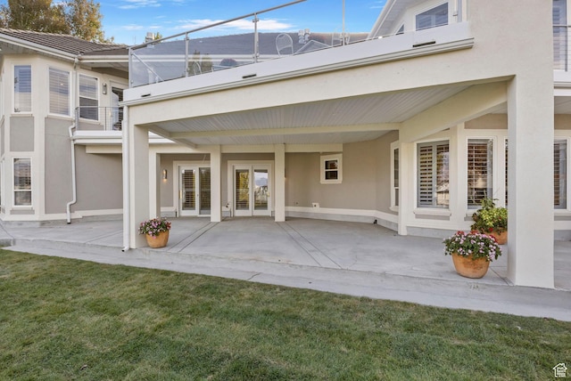back of house with stucco siding, a patio, and a yard