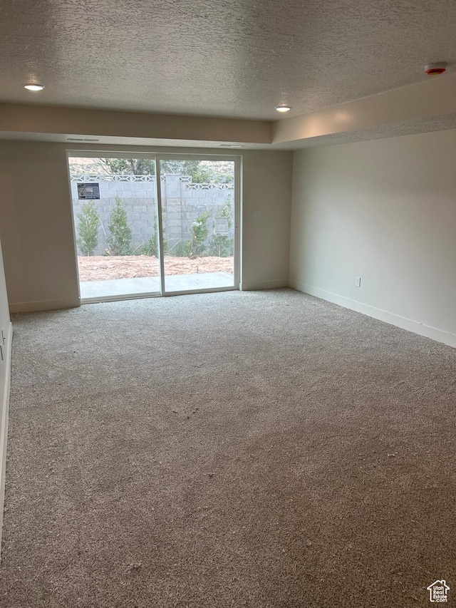 carpeted empty room featuring a textured ceiling, baseboards, and a smoke detector