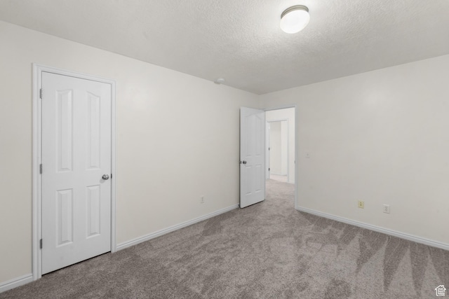 unfurnished bedroom with carpet, baseboards, and a textured ceiling