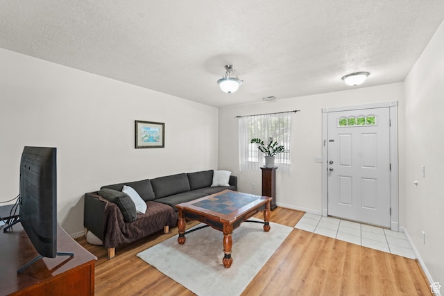 living room featuring light wood-style floors, a textured ceiling, and baseboards