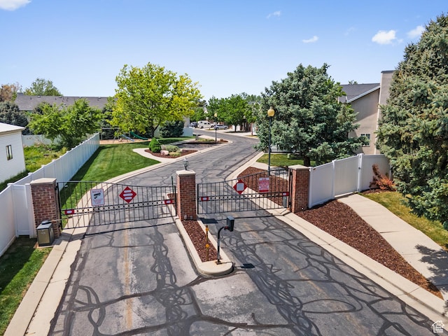 view of asphalt road with street lights, a gate, traffic signs, and a gated entry