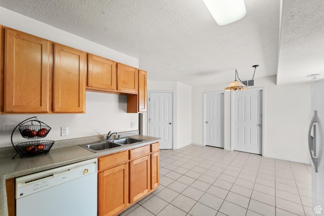 kitchen with white appliances, a sink, a textured ceiling, light tile patterned floors, and baseboards