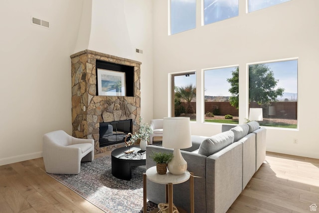 3134 S 355 W, Washington, UT 84780 - living room featuring a stone fireplace, plenty of natural light, light wood-style floors, a high ceiling, and baseboards