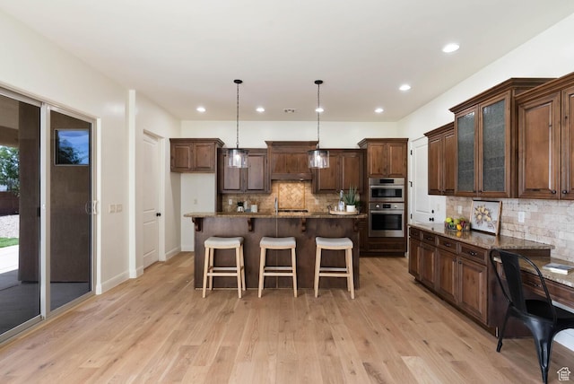 3134 S 355 W, Washington, UT 84780 - kitchen featuring double oven, backsplash, a breakfast bar, light wood-type flooring, and decorative light fixtures
