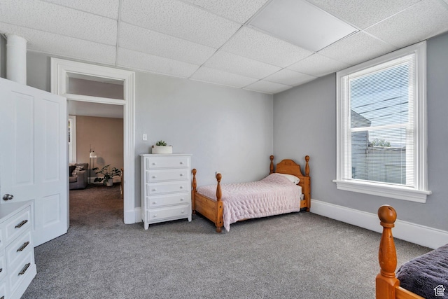 carpeted bedroom with a paneled ceiling and baseboards