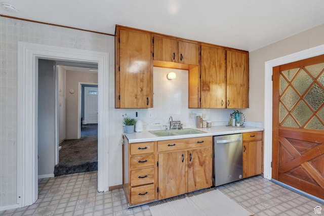 kitchen with stainless steel dishwasher, light floors, a sink, light countertops, and brown cabinetry